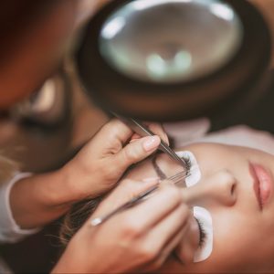Beautician applying extended eyelashes to model at the beauty salon.